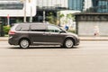 Toyota Sienna in motion on the city street. 5-door minivan driving on the road, side view