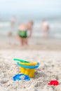 Toys at the beach - plastic yellow bucket, rake, spatula, molds on a sandy seaside beach Royalty Free Stock Photo