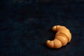 Toys for kids in food theme. One Croissant on dark background. Food and toy concept. Object made from plastic