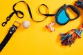 Toys -multi coloured rope, ball, leather leash and bone. Accessories for play and training on yellow background top view
