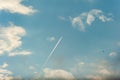 The trace of the plane in the blue sky among the clouds.