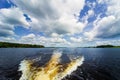 Trace on the water from the movement of the boat. Volga river. Blue sky with white clouds Royalty Free Stock Photo