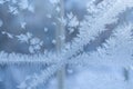 Tracery frosty pattern of two intersecting stripes on winter blue window.