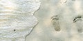 Traces of feet on the sand. Texture background Footprints of human feet on the sand near the water on the beach