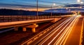 Traces of headlights from cars moving at night on the bridge, illuminated by lanterns. Abstract cityscape with highway at dusk Royalty Free Stock Photo