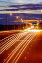 Traces of headlights from cars moving at night on the bridge, illuminated by lanterns. Abstract cityscape with highway at dusk Royalty Free Stock Photo