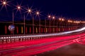 Traces of headlights from cars moving at night on the bridge, illuminated by lanterns. Abstract cityscape with highway at dusk Royalty Free Stock Photo