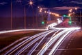 Traces of headlights from cars moving at night on the bridge, illuminated by lanterns. Abstract cityscape with highway at dusk Royalty Free Stock Photo