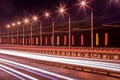 Traces of headlights from cars moving at night on the bridge, illuminated by lanterns. Abstract cityscape with highway at dusk Royalty Free Stock Photo