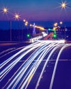 Traces of headlights from cars moving at night on the bridge, illuminated by lanterns. Abstract city landscape with highway Royalty Free Stock Photo