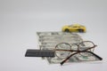 Track of dollar bills. Toy car on a white background with glasses and a calculator, the concept of car ownership cost