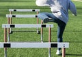 Track hurdler running one leg over hurdels on a turf field