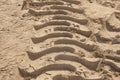 Track of a tractor or truck on sand in ocher tones, footprint of a car on dirt or mud, large tire mark on asphalt Royalty Free Stock Photo