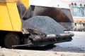 Tracked paver laying fresh asphalt pavement during road constru