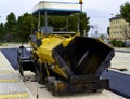 Tracked paver laying fresh asphalt pavement