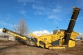 A tracked stone crusher machine under a blue sky with clouds Royalty Free Stock Photo