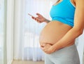 Tracking her pregnancy with a mobile app. a pregnant woman using a mobile phone at home. Royalty Free Stock Photo