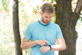 Tracking his training with a sports watch. Handsome athlete using smart watch during training outdoor. Sportsman