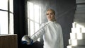 Tracking shot of Young concentrated fencer woman training fencing exercise in studio indoors