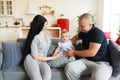 Tracking shot of joyous mother, father and little son sitting together on sofa at home, smiling and playing to boy