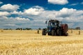 Tractor with bale machine for harvesting straw in the field and making large round bales. Agricultural work, harvesting Royalty Free Stock Photo