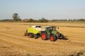 A tractor with a baler is making straw bales in the dutch countryside in summer