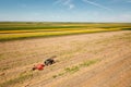 Tractor baling hay, sunflower fields and blue sky in the background Royalty Free Stock Photo