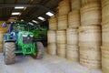 Tractor and barley straw bales stacked in barn