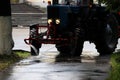 Tractor with a barrel on a trailer pours water over the city sidewalks, streams of water flow down to the ground Royalty Free Stock Photo