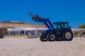 Tractor and beautiful gulls flying over blue skies and approaching land and beach bathers