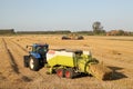 A tractor with a baler is making straw bales in the dutch countryside in summer