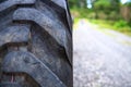 Tractor black tire closeup and road perspective view. Heavy machinery detail. Road construction site concept Royalty Free Stock Photo