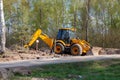 A tractor with a bucket digs a hole in the forest Royalty Free Stock Photo