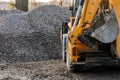 A tractor with a bucket loads stone gravel at a construction site