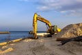 Tractor with a bucket on the sea beach. The excavator works with the coastline. Royalty Free Stock Photo