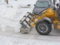 Tractor bulldozer clears snow in the parking lot for cars. Winter works Royalty Free Stock Photo