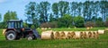 Tractor carrying hay bale rolls and collecting them on a field. Royalty Free Stock Photo