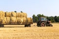 Tractor carrying hay bale rolls - stacking them on pile. Agricultural machine collecting bales of hay on a field Royalty Free Stock Photo