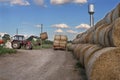 Tractor carrying hay bale rolls - stacking them on pile. Agricultural machine collecting bales of hay on a field Royalty Free Stock Photo