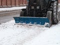 Tractor cleaning sidewalk from snow with snow plow and rotating brush Royalty Free Stock Photo