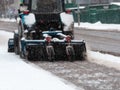 Tractor cleaning sidewalk from snow with snow plow and rotating brush Royalty Free Stock Photo