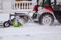 Tractor cleaning snow at city street and a parking lot after snowfall Royalty Free Stock Photo