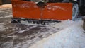 A bucket close-up cleans the sidewalk from snow. The tractor cleans the pavement in winter. Tractor cleaning the road from the Royalty Free Stock Photo