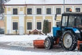 A tractor cleans snow in the city in winter after a snowfall. Cleaning city streets from snow. Tractor driver at work in the city