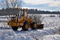 Tractor clears road in village on winter sunny day