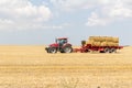 Tractor collecting straw bales during harvesting in the field at nice blue sunny day Royalty Free Stock Photo