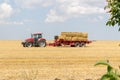 Tractor collecting straw bales during harvesting in the field at nice blue sunny day Royalty Free Stock Photo