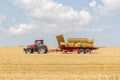 Tractor collecting straw bales during harvesting in the field at nice blue sunny day Royalty Free Stock Photo