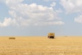 Tractor collecting straw bales during harvesting in the field at nice blue sunny day Royalty Free Stock Photo