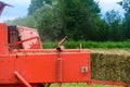 The tractor collects dry hay in the field, the hay presses the bale press, work in the field Royalty Free Stock Photo